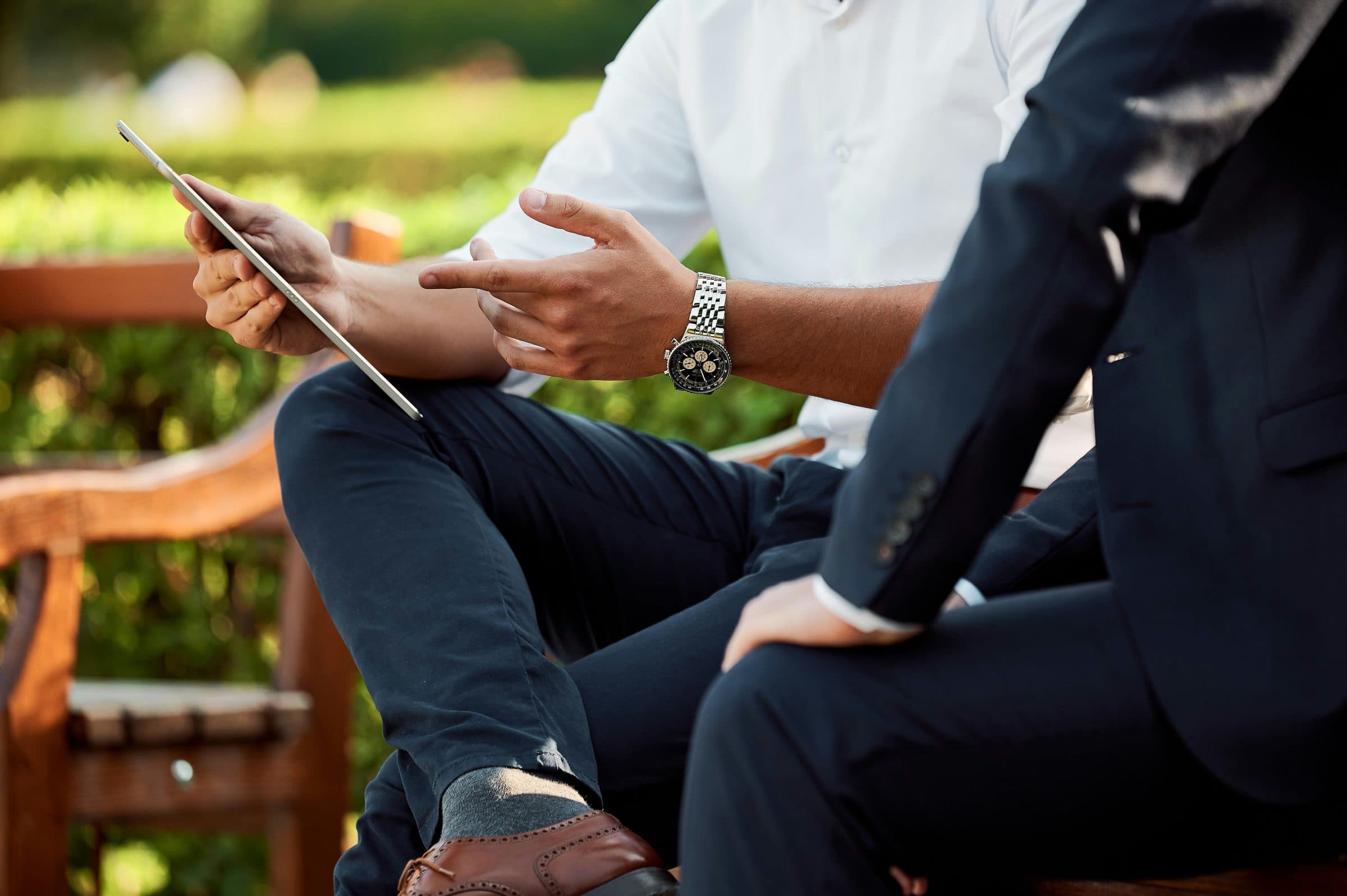 Two business professionals reviewing plans on a tablet together on an outdoor bench