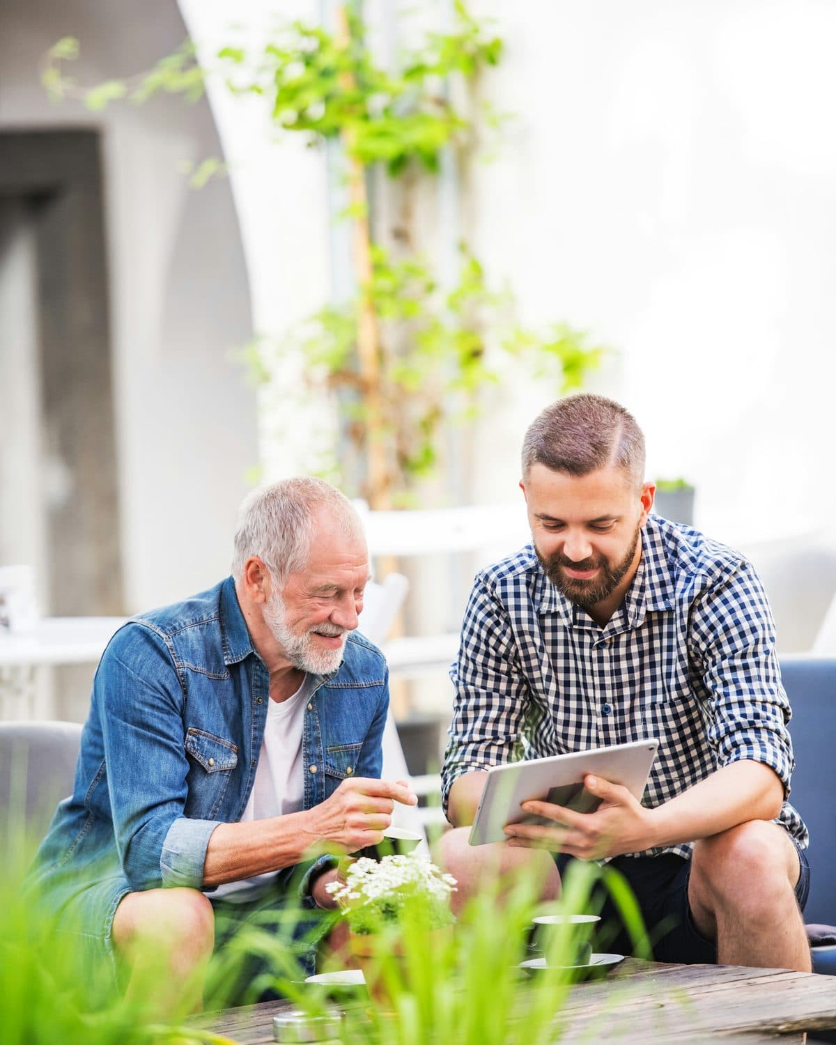 An experienced care-business owner and an advisor reviewing plans together on a tablet in a warm outdoor setting