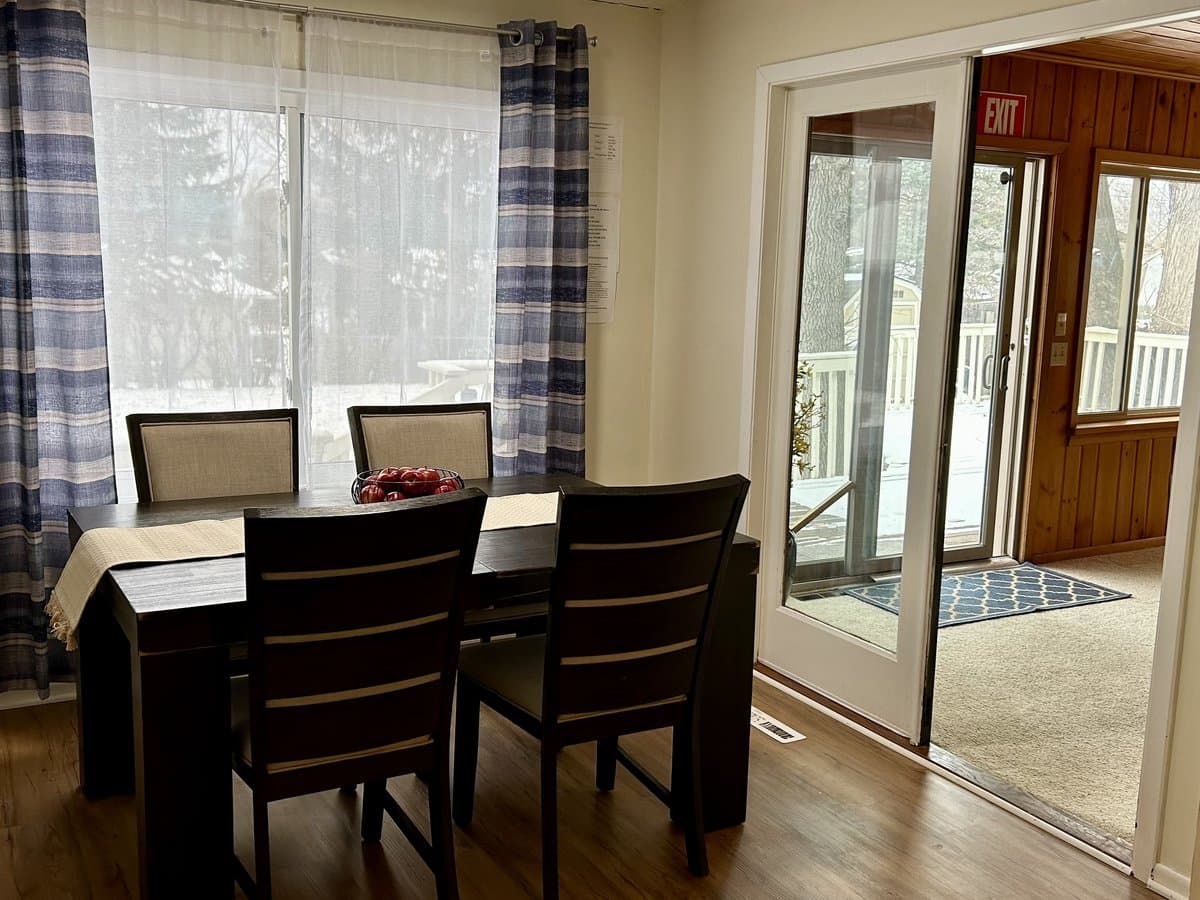 Dining area with a table for four beside a sliding door opening to the four-season porch