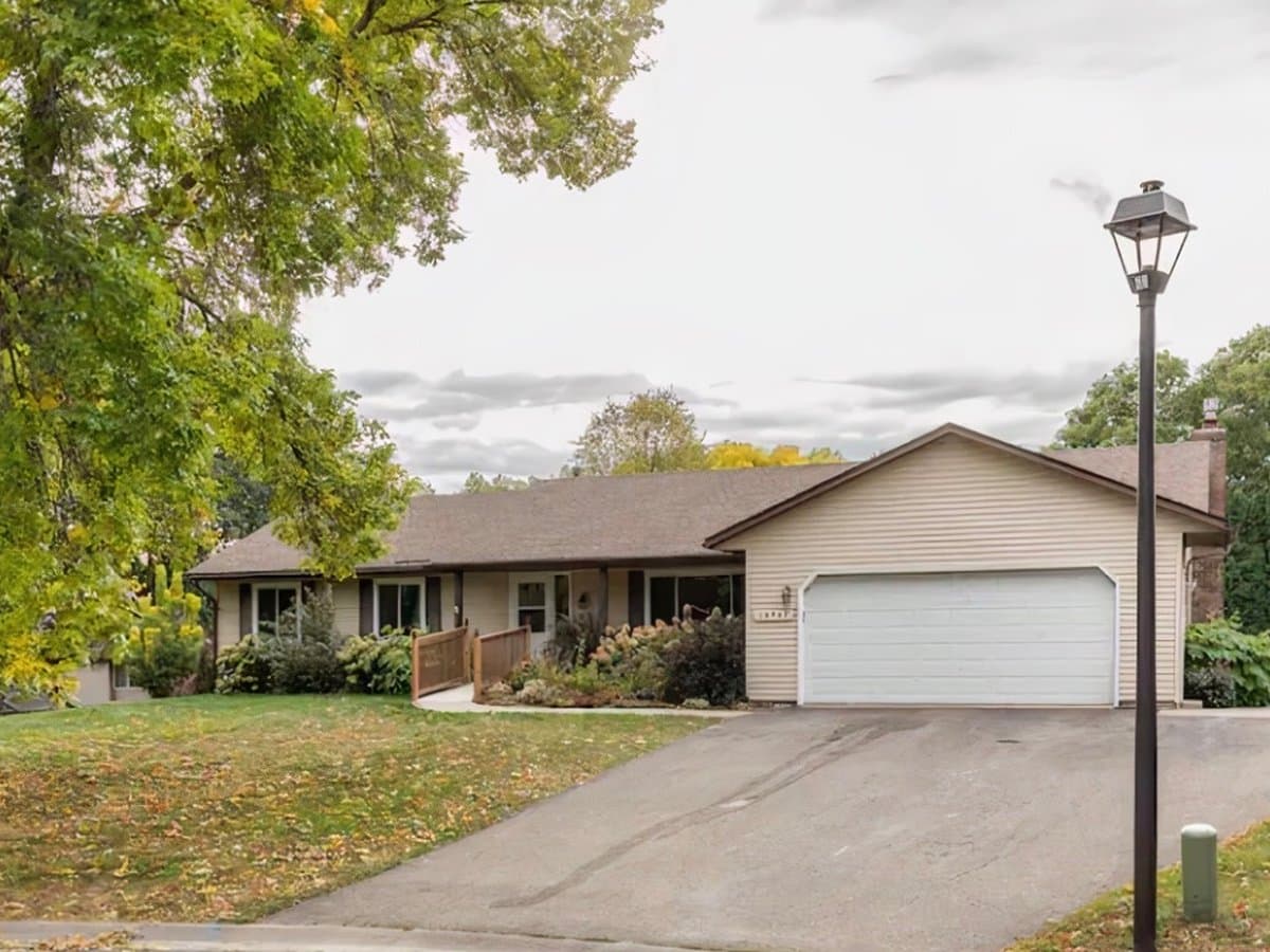 Single-story residential assisted living home with an accessible ramp, landscaped entry, and two-car garage in Maple Grove, MN